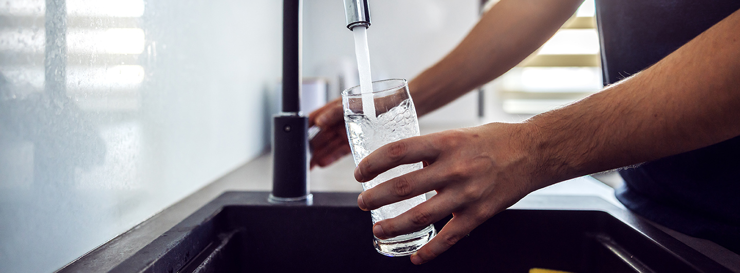 Person pouring a glass of water from the sink