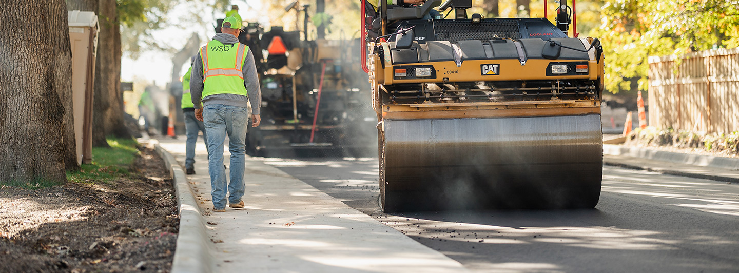 Steam roller and construciton workers working on a road
