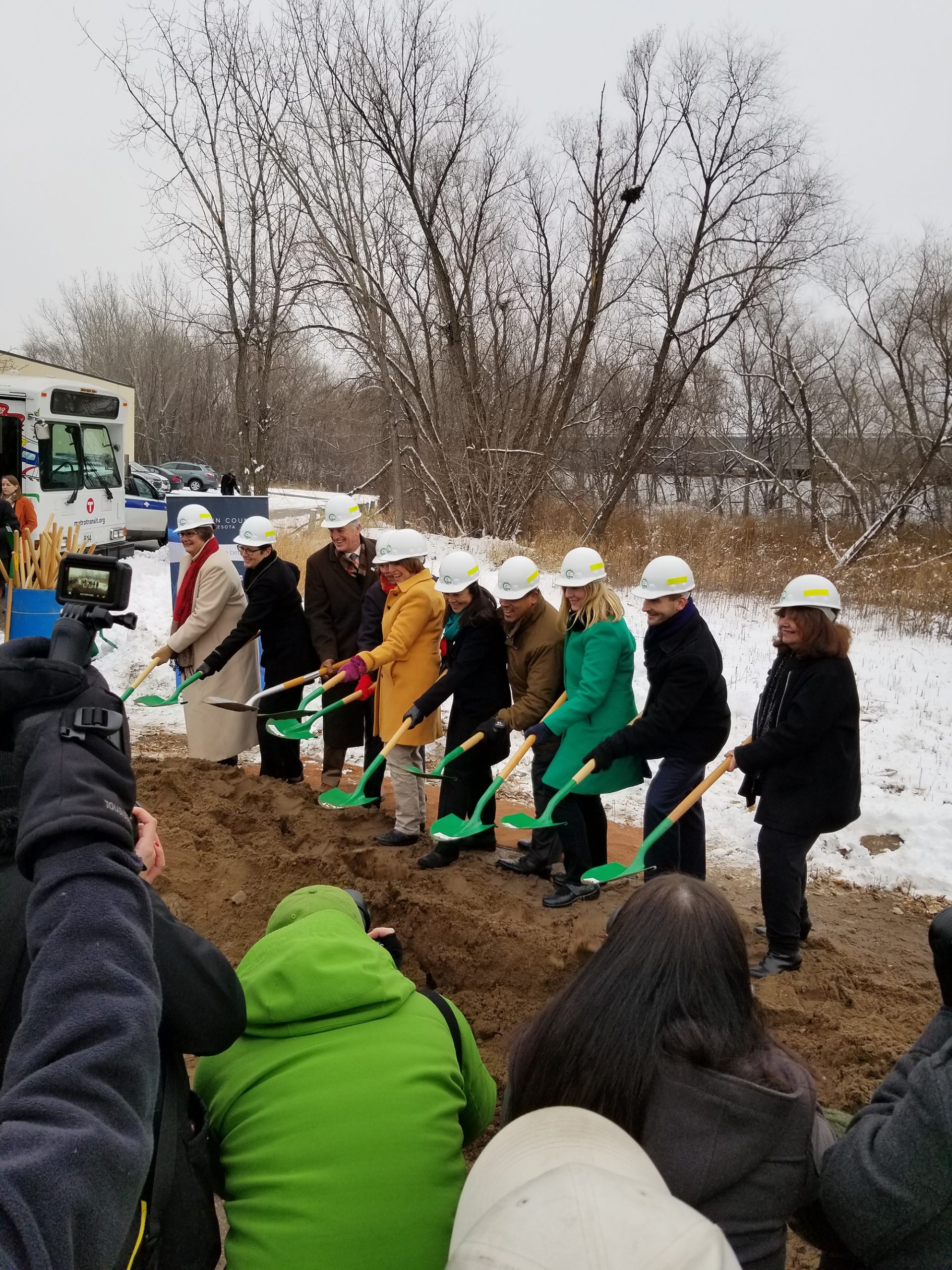 People holding green shovels in a line