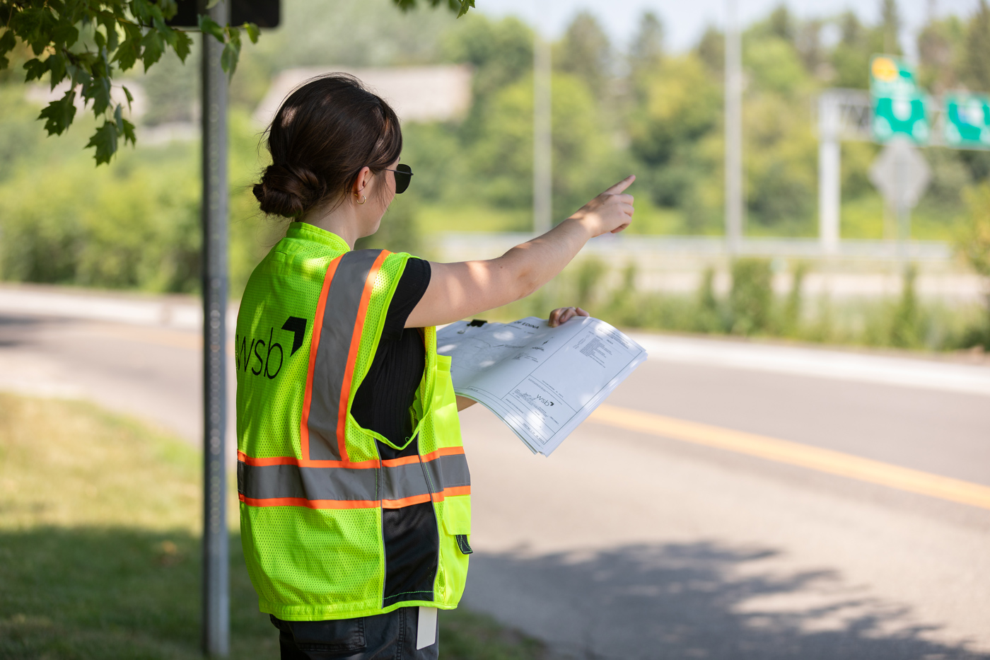 Engineer wearing a safey vest holding papers next to a roadway