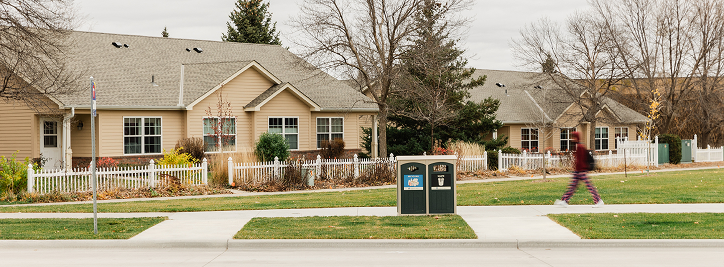 Person walking down a sidewalk next to a housing development