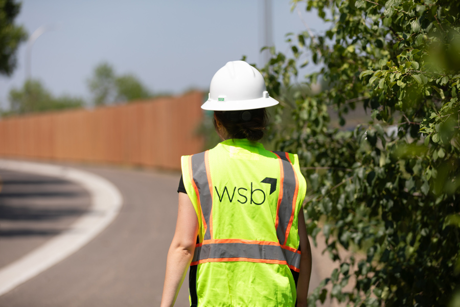 Engineer wearing protective safety gear walking next to a roadway or street
