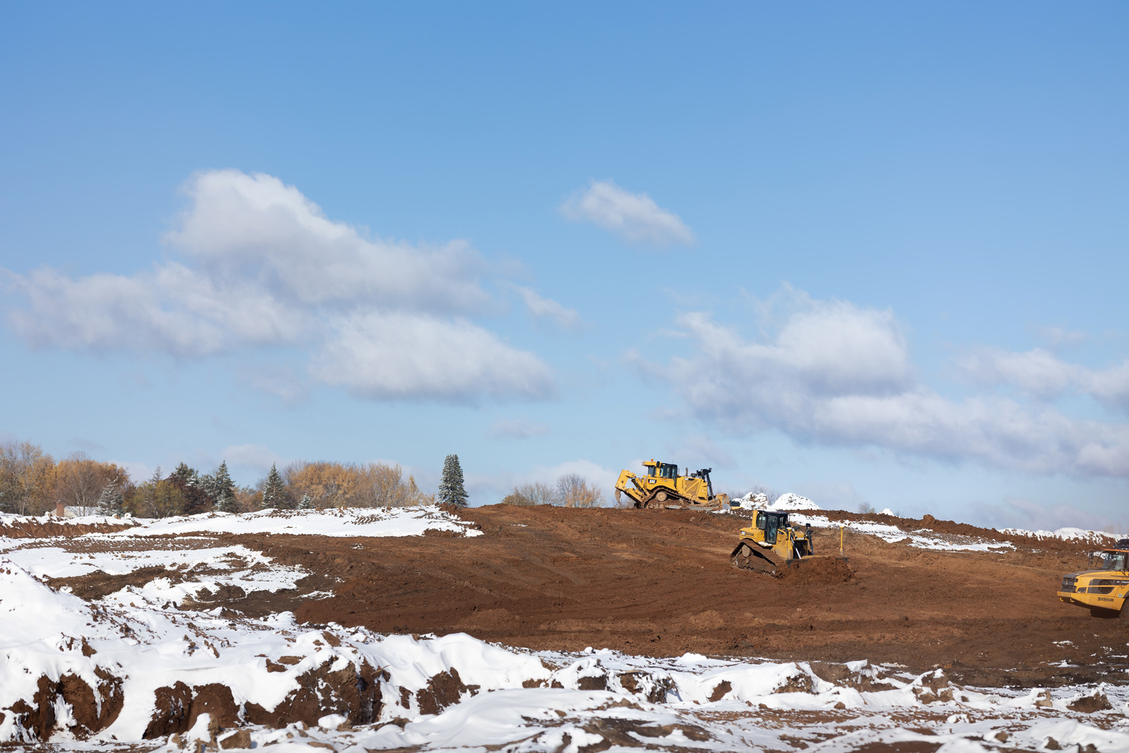 Construction equipment moving dirt in a field