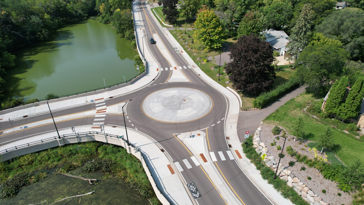 Road near a body of water with a bridge and roundabout