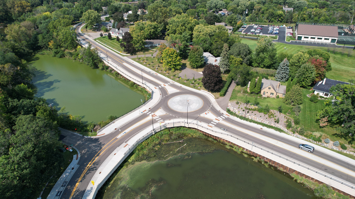 Road near a body of water with a bridge and roundabout