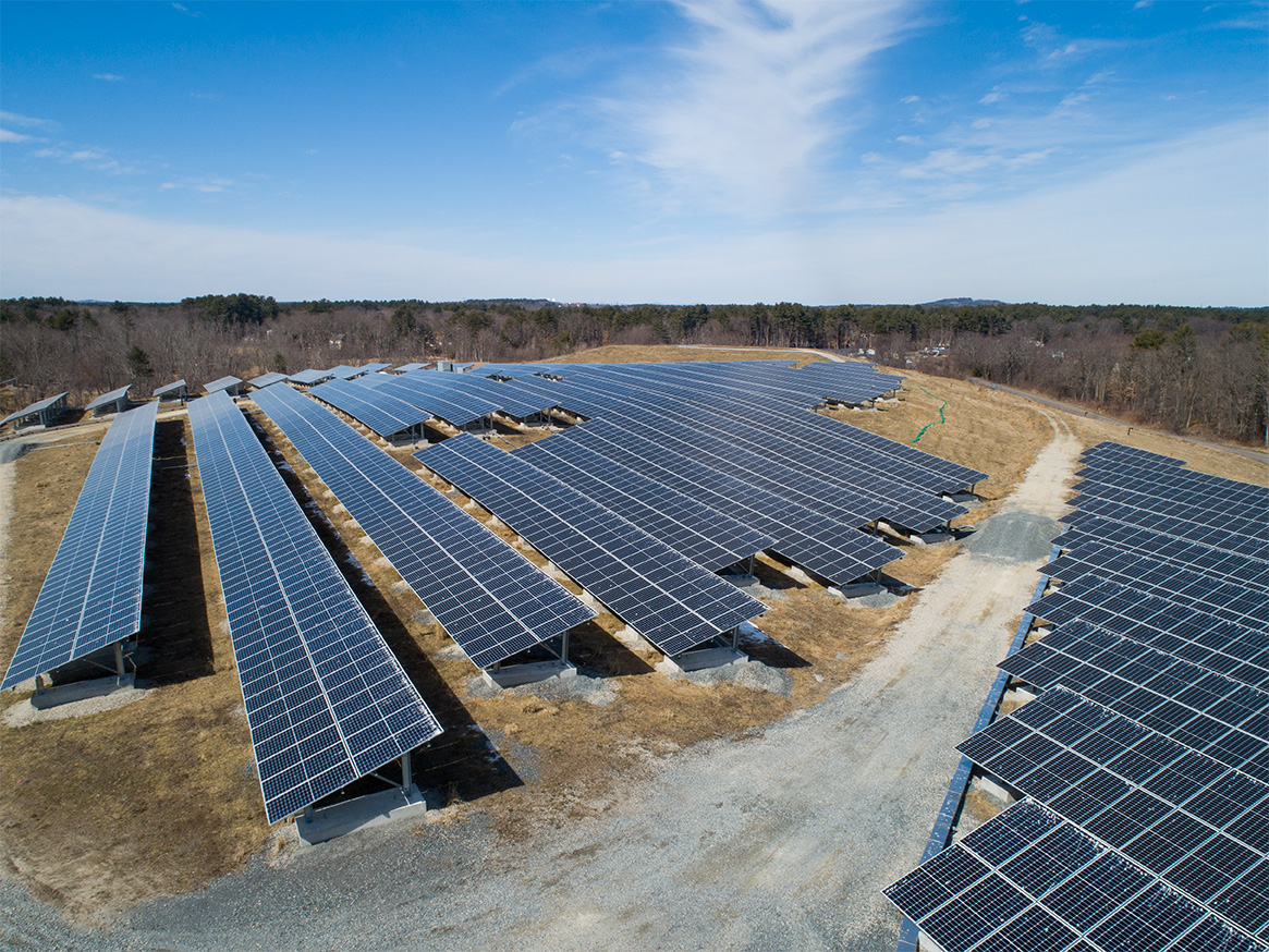 Aerial view of the Tewksbury solar array constructed on a capped landfill, showing rows of ground‑mount photovoltaic panels and access roads in Tewksbury, Massachusetts.