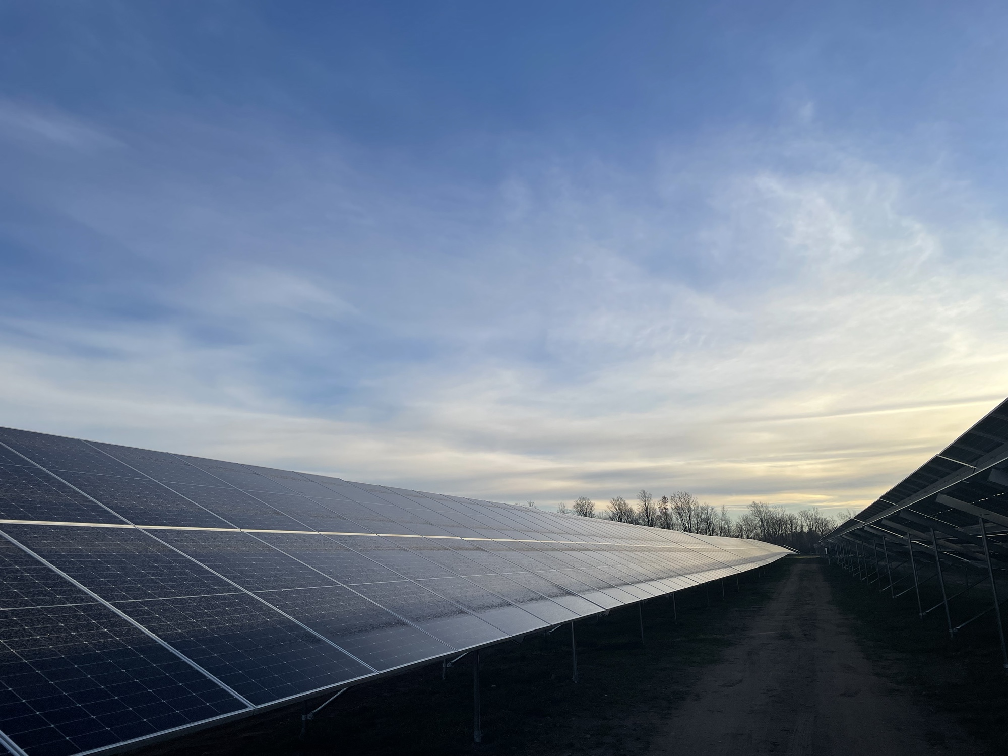 Perspective view along rows of agrivoltaic solar panels at the Constable Solar project in Constable, New York, illustrating panel spacing and site layout.