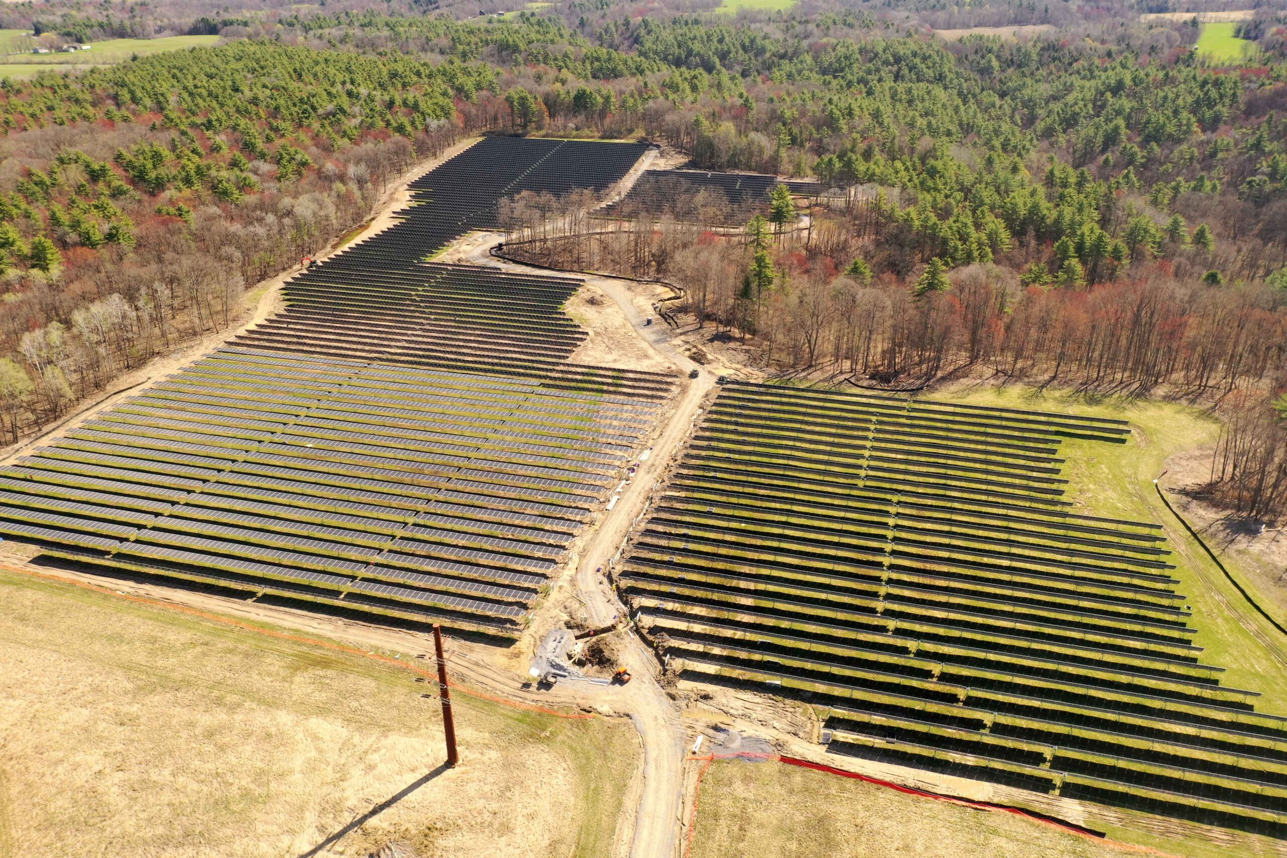 Aerial view of the Fort Edward Community Solar project in Greenwich, New York, showing rows of single‑axis tracking solar panels across the site.