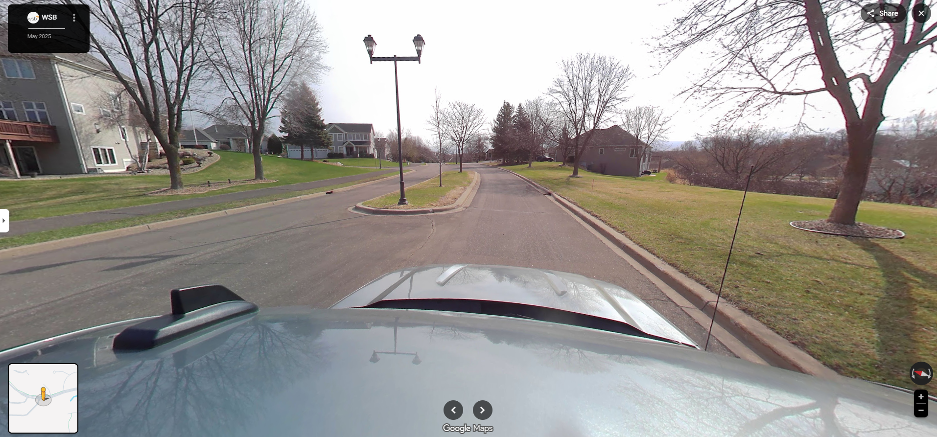 Street-level view of a rural gravel road curving to the right, with trees and grass along both sides and a yellow curve warning sign.