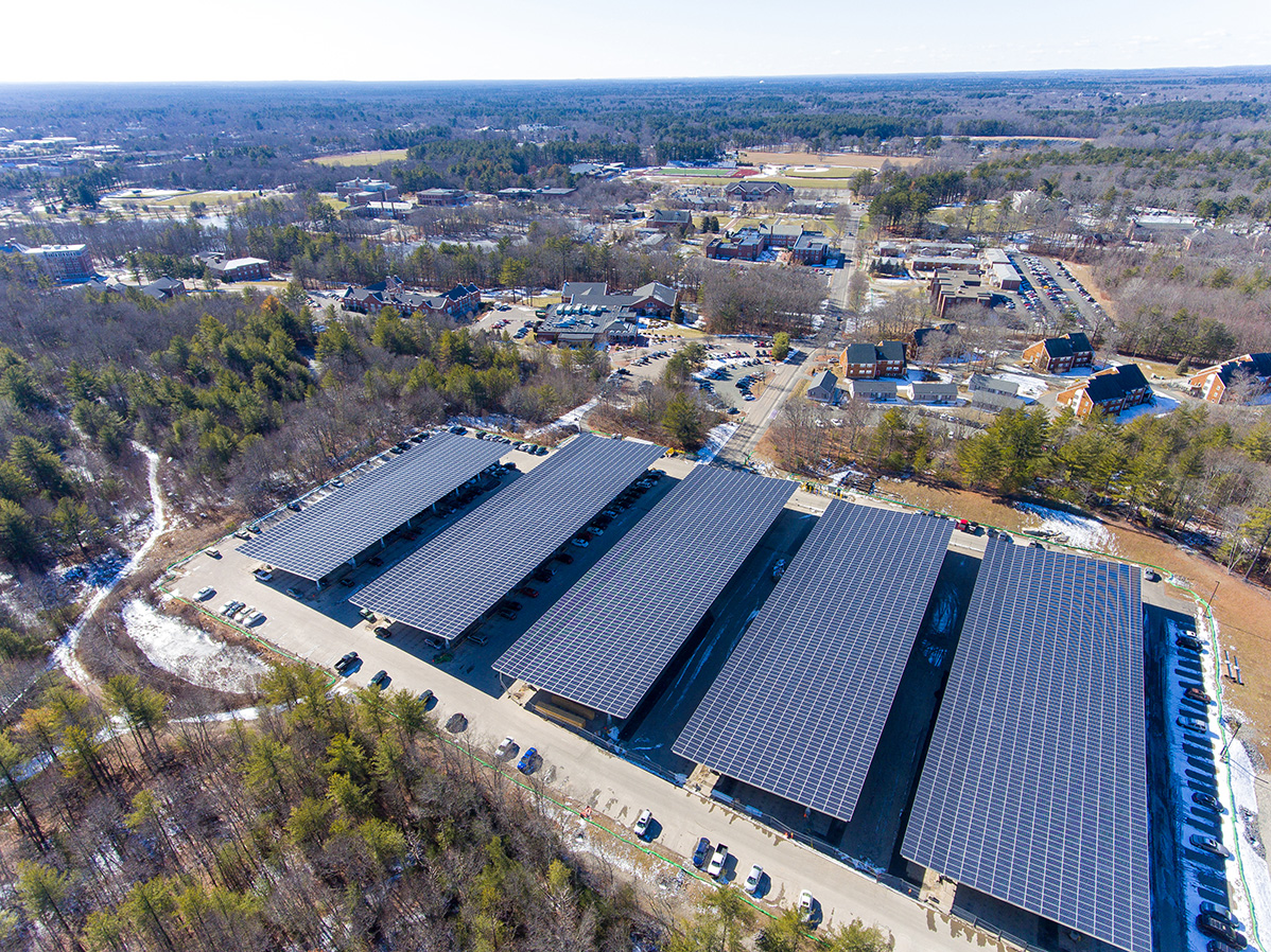 Aerial view of five solar carport structures at Stonehill College in Easton, Massachusetts, showing the full carport array integrated within the campus parking area.