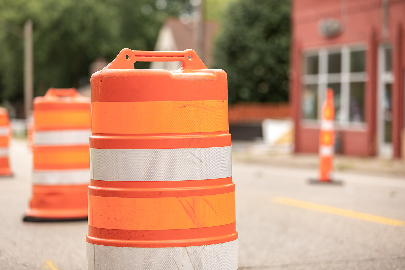 Orange traffic barrel with white reflective stripes on a paved street.