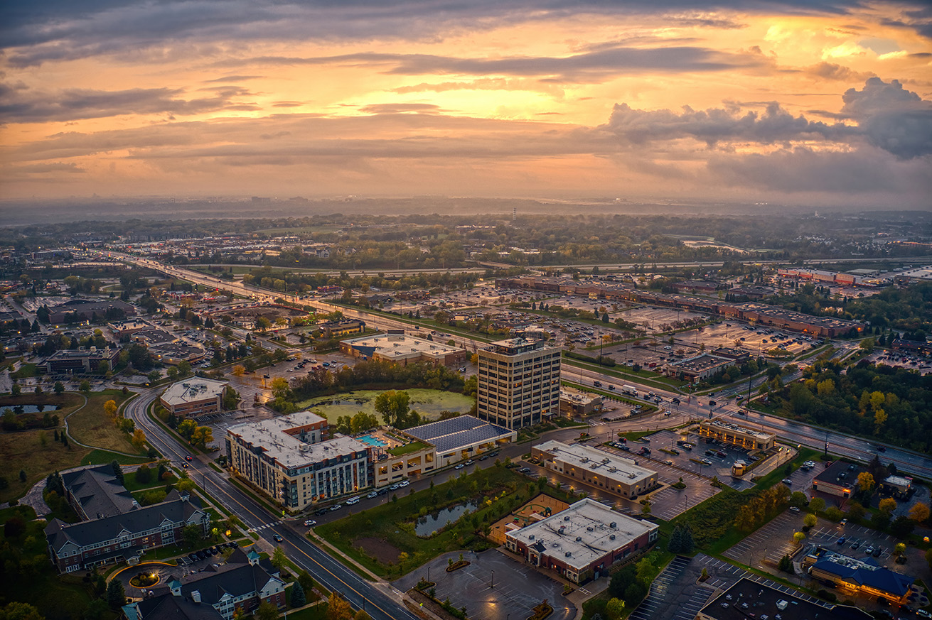 Aerial view of Eagan, Minnesota, showing commercial buildings, roadways, and surrounding development at sunset.