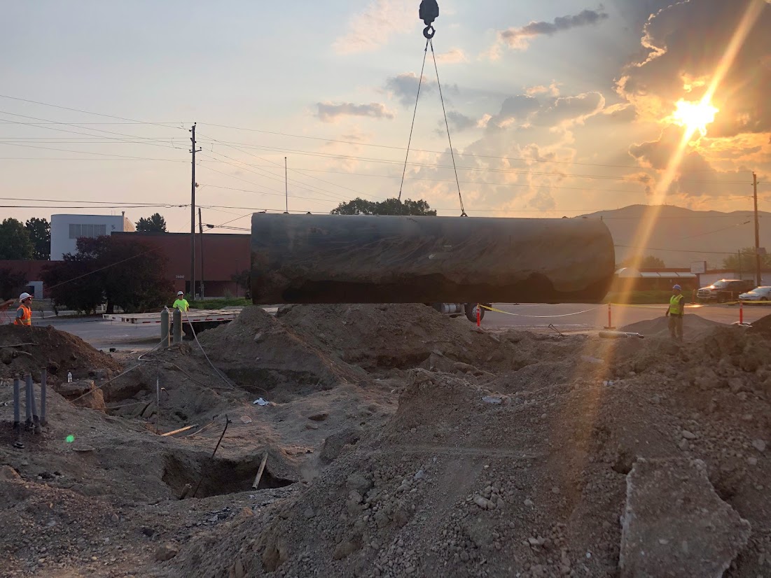 Large underground utility structure being lowered into an excavation at a construction site during environmental assessment and infrastructure work.