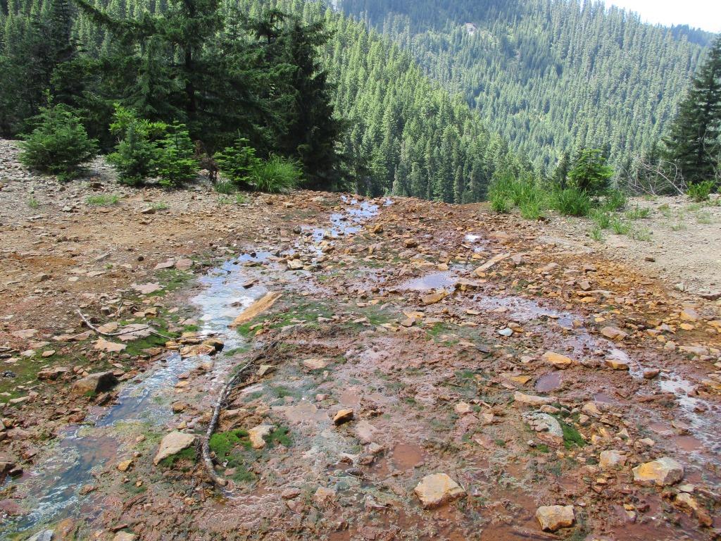 Construction crew installing wire mesh slope stabilization measures on a steep mountainside at the Champion Mine site.