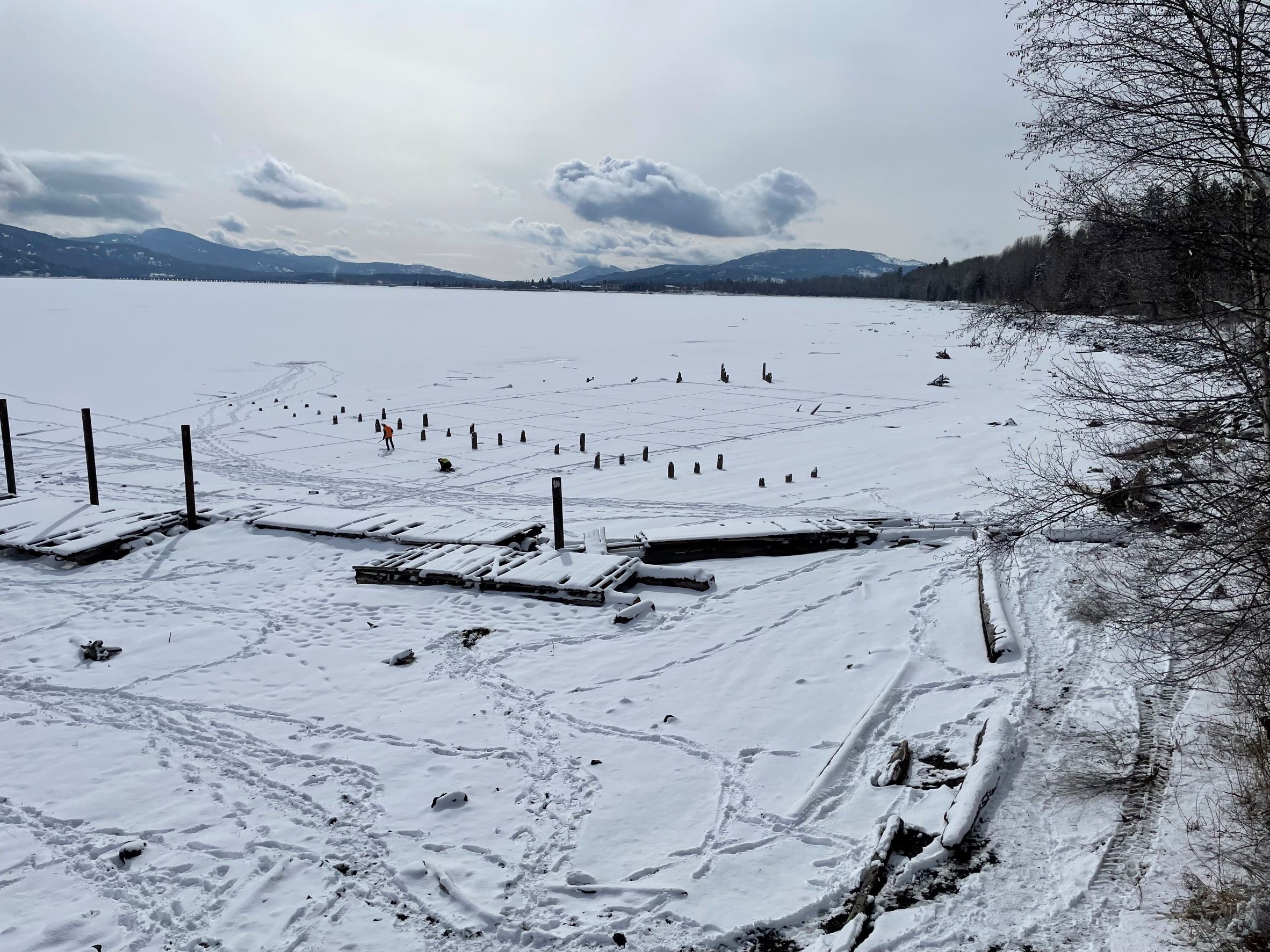 Snow-covered shoreline and frozen Lake Pend Oreille showing exposed pilings and former industrial features at the Ponderay Smelter Site.