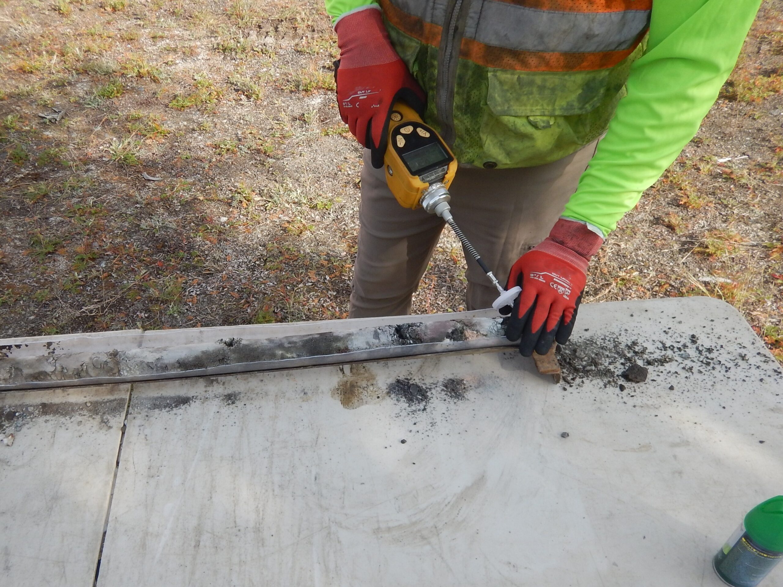 A gloved worker holds a cylinder-shaped soil core sample.